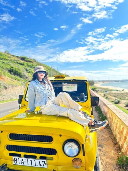 A person sitting on a yellow vehicle on a road with a coastal landscape in the background. 2