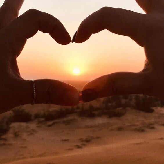 Hands forming a heart shape against a sunset. 1