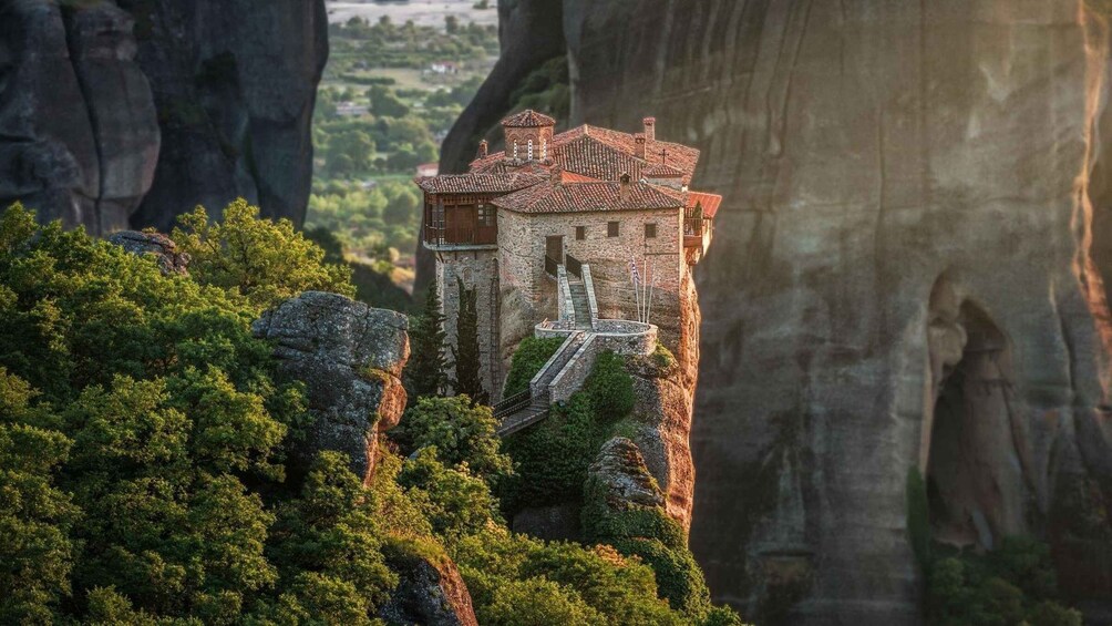 A medieval tower perched on a cliff surrounded by lush greenery and dramatic rock formations. 1