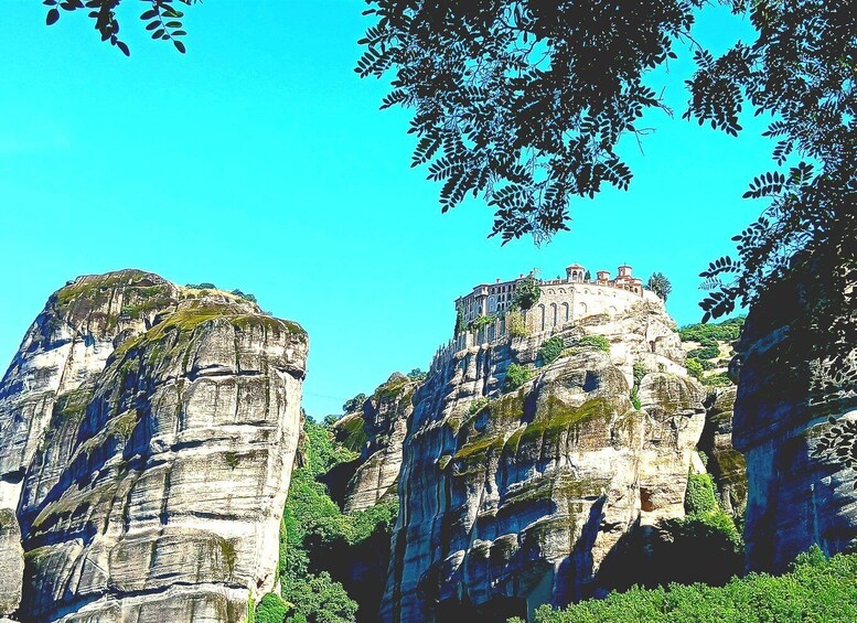 A rock formation with a building on top, surrounded by greenery. 5