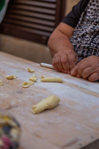 Hands shaping dough on a wooden surface. 5