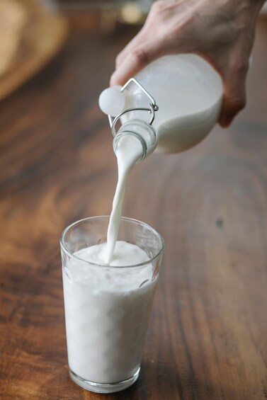A hand pouring milk into a glass. 3