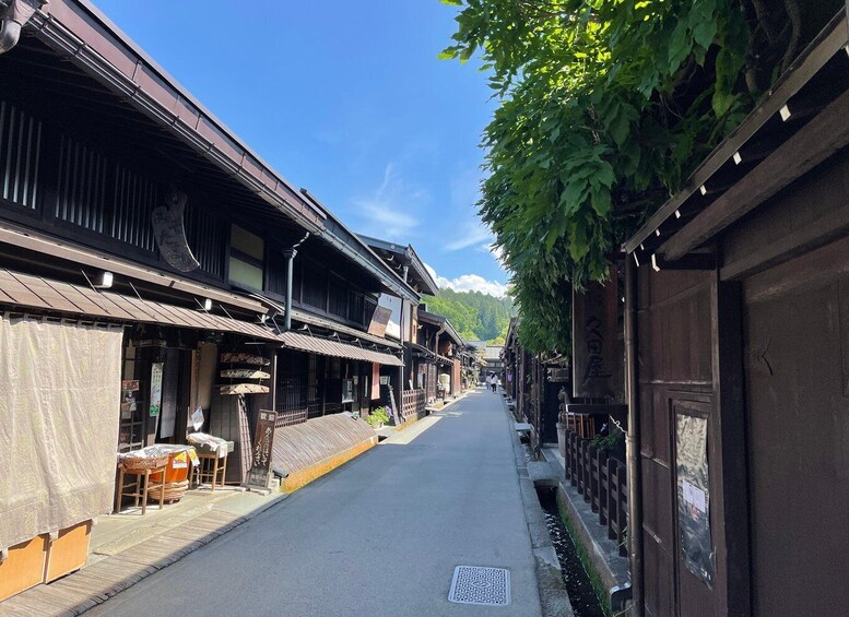 A narrow street lined with traditional wooden buildings, a clear blue sky, and a mountain in the background. 4