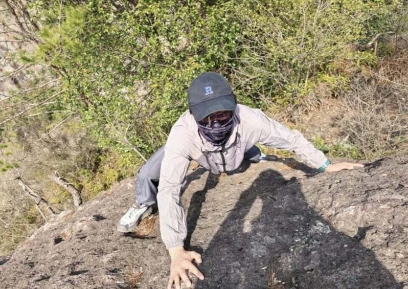 A person climbing a rocky hill with sparse vegetation. 5