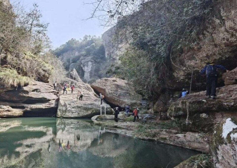 A group of people climbing a rocky outcrop near a body of water. 2
