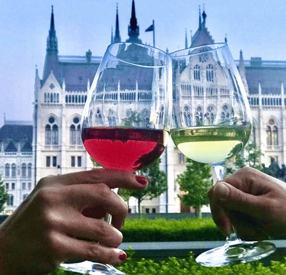 Two hands holding wine glasses with a historic building in the background. 2
