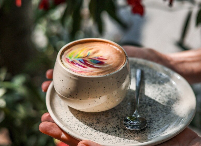 A ceramic cup with latte art on a saucer, held by a hand. 4