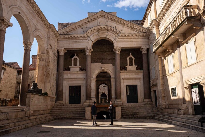 An ancient building with classical architecture, including arches and columns, and a central doorway. 3