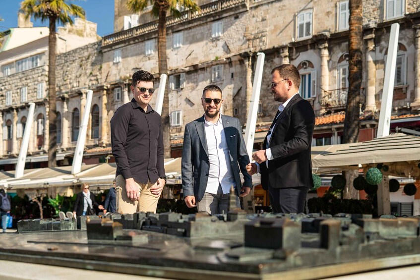 Three men standing in front of a model of a building. 5