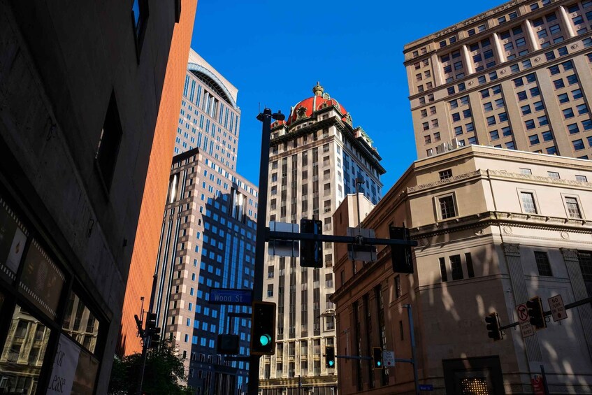 A cityscape with a prominent building featuring a red dome, a blue building with reflective windows, and a traffic light displaying a green signal. 1