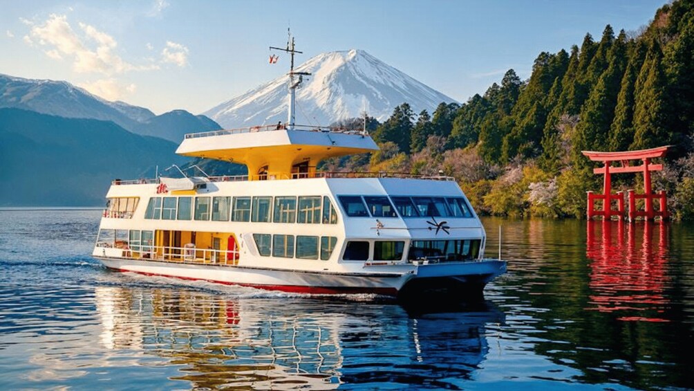 A white and red boat on calm water with a snow-capped mountain in the background and a red torii gate on the right. 3