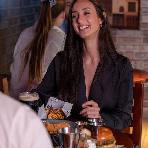 A person seated at a table with a burger, a drink, and a menu. 2