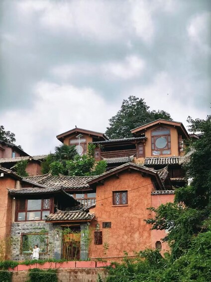 A traditional multi-story building with ornate wooden balconies and tiled roofs, surrounded by lush greenery. 1