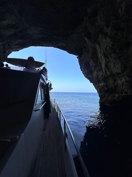 A boat docked at a cave opening with a view of the sea. 3
