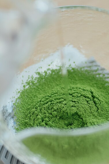 A close-up of a green powder being poured into a container. 2