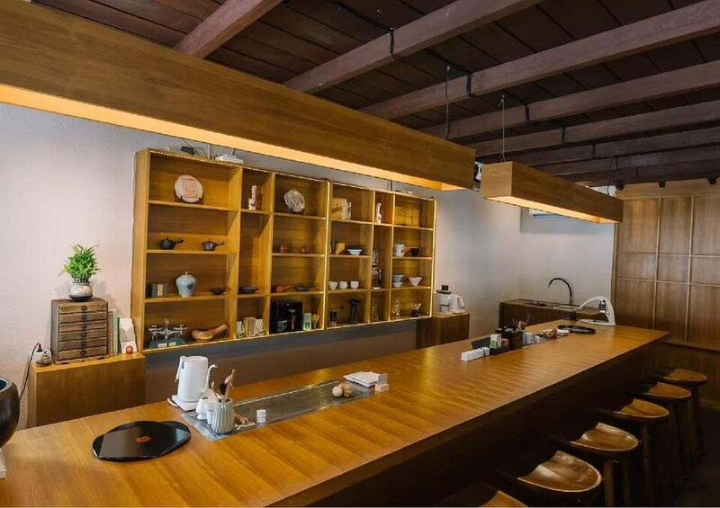 A modern bar with wooden shelves, stools, and a long counter. 3