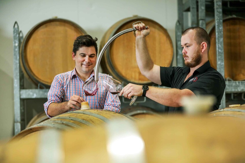 Two people in a winery, one pouring wine into a glass. 3