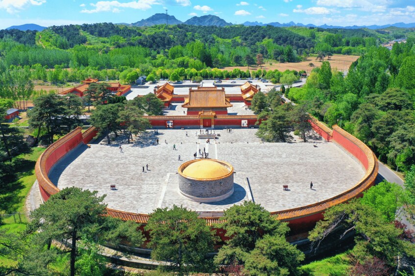 A traditional Chinese courtyard with a central circular structure, surrounded by buildings with red-tiled roofs. 4