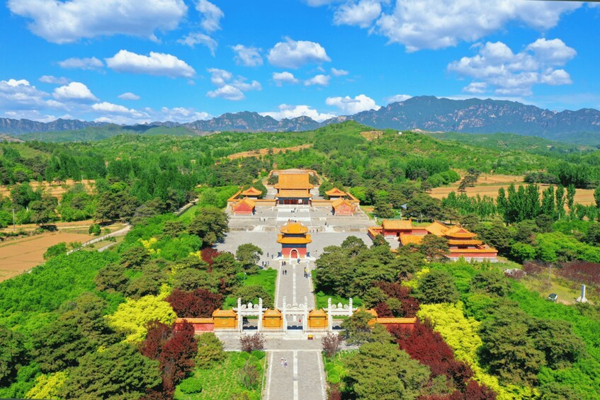A traditional temple complex with multiple buildings, surrounded by lush greenery and mountains in the background. 3