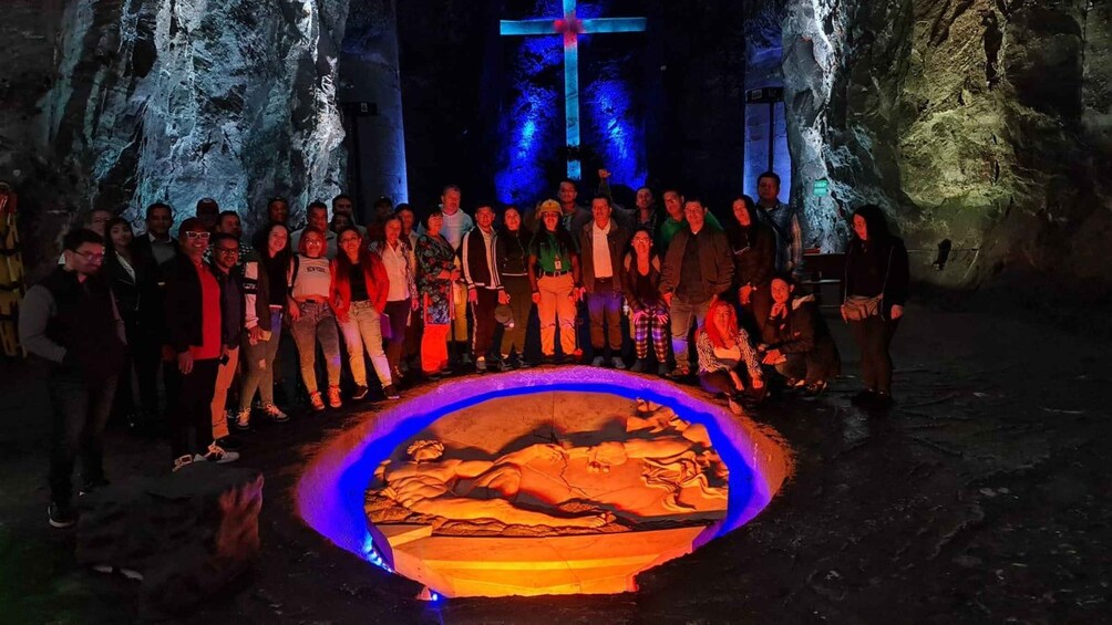 A group of people in a cave with a cross illuminated in the background. 5