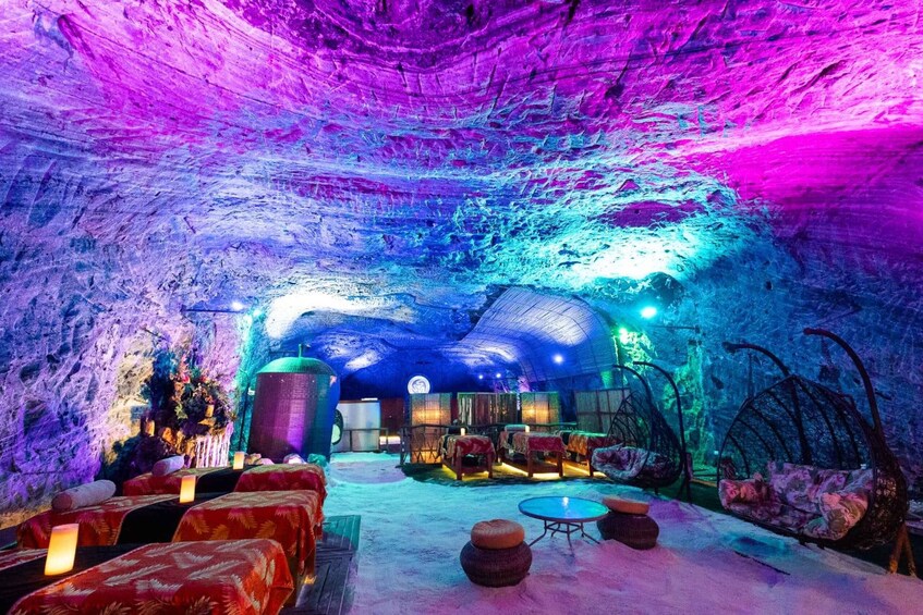 An ice cave interior with seating and tables, illuminated by colorful lights. 3