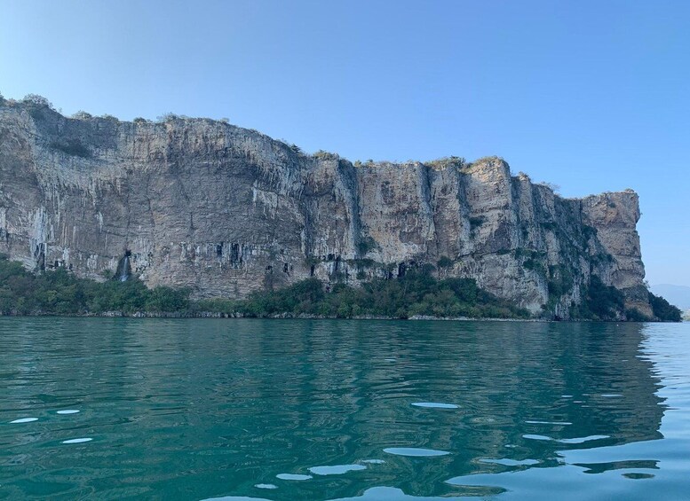 A large cliff by a calm body of water. 3