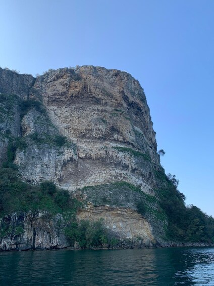 A large cliff with layered rock formations and sparse vegetation. 4