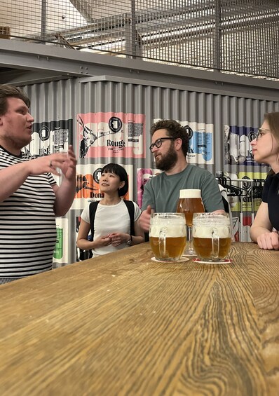 A group of people sitting at a table with four glasses of beer. 1