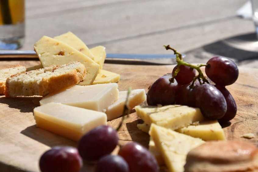 A wooden board with cheese, grapes, and bread. 3