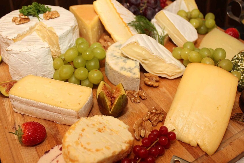 A variety of cheeses and fruits on a wooden board. 2