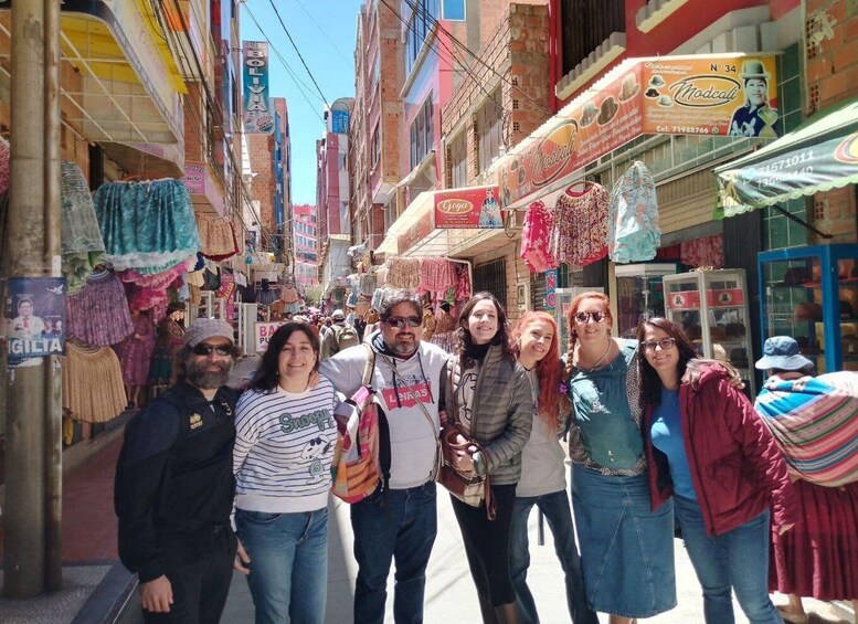 A group of people walking down a narrow street lined with colorful shops and signs. 5