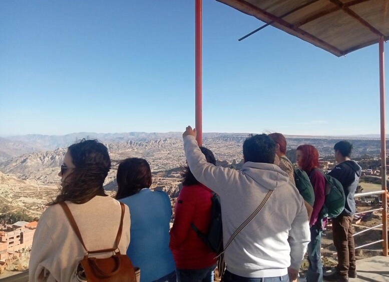 A group of people standing on a viewing platform overlooking a mountainous landscape. 2
