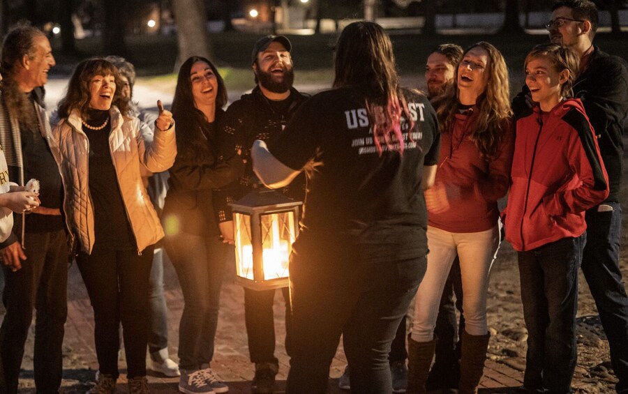 A group of people outdoors at night, some holding a lantern. 2