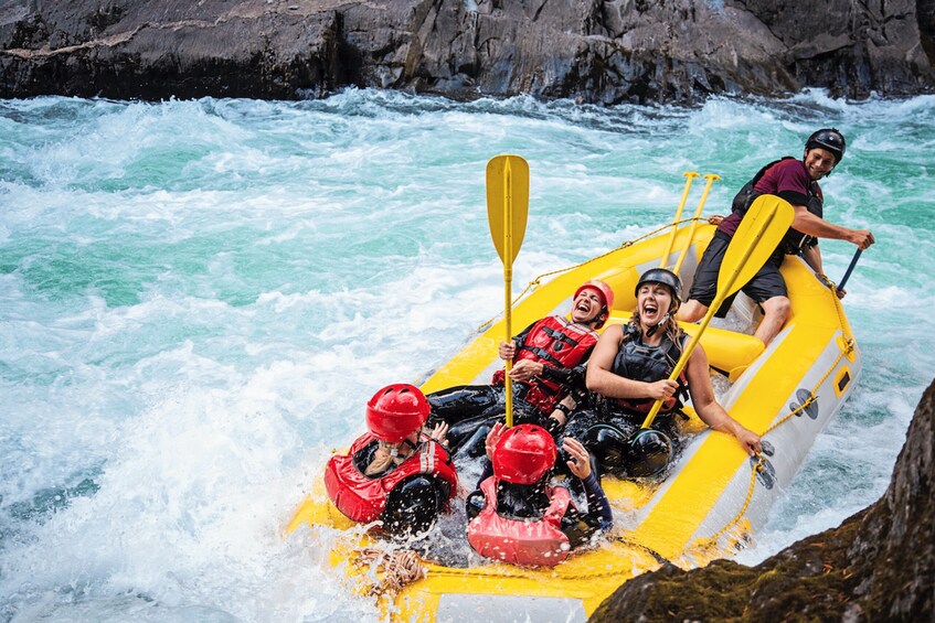 A group of people in a yellow raft navigating through a river with rapids. 1