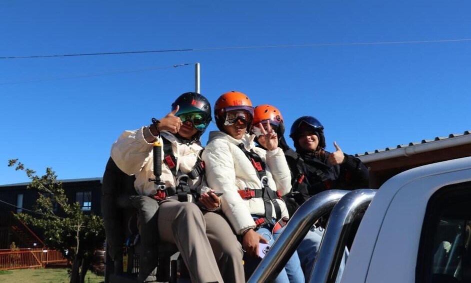 Four people in helmets and harnesses, sitting in a vehicle. 2