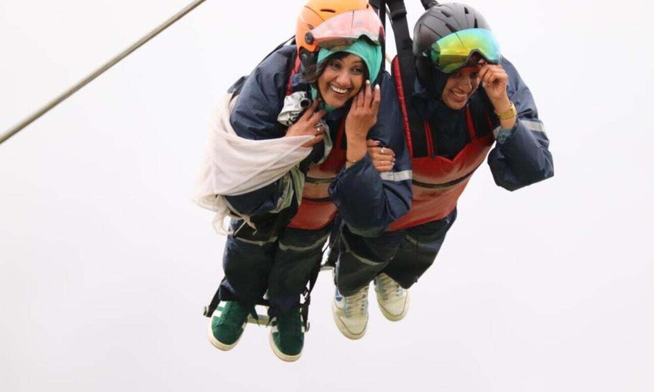 Two people bungee jumping with safety harnesses and helmets. 3