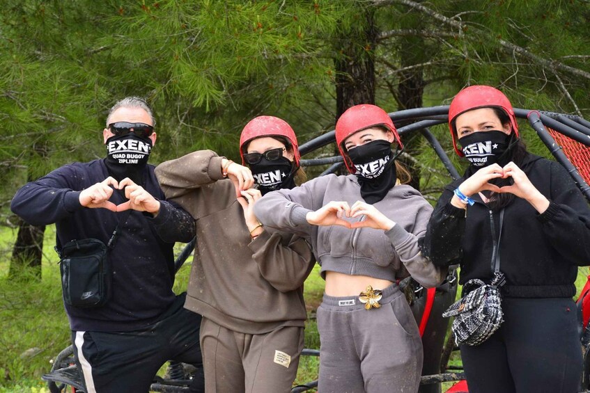 Four people making heart shapes with their hands, wearing matching black and red helmets, standing near a red vehicle. 5