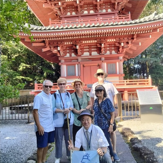 A group of people in front of a traditional red pagoda with a tiled roof and a signboard. 3