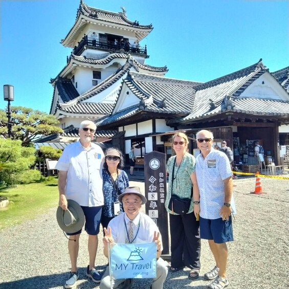 A group of people in front of a traditional Japanese building with a tiled roof and white walls. 2