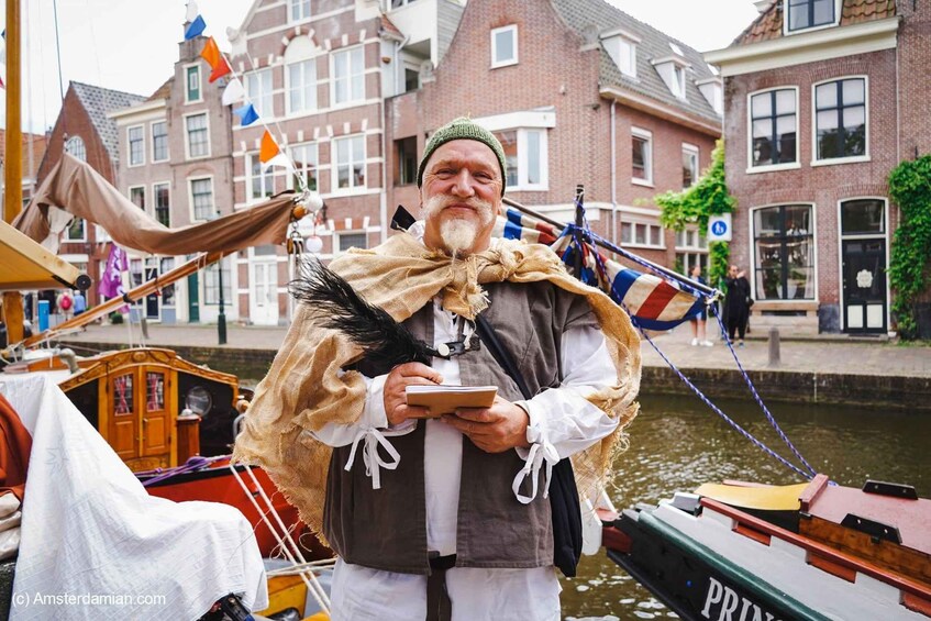 A person in historical costume standing by a canal with boats and traditional buildings in the background. 1