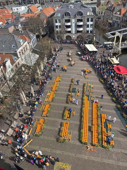 A public square with people gathered around a central area with orange decorations. 5
