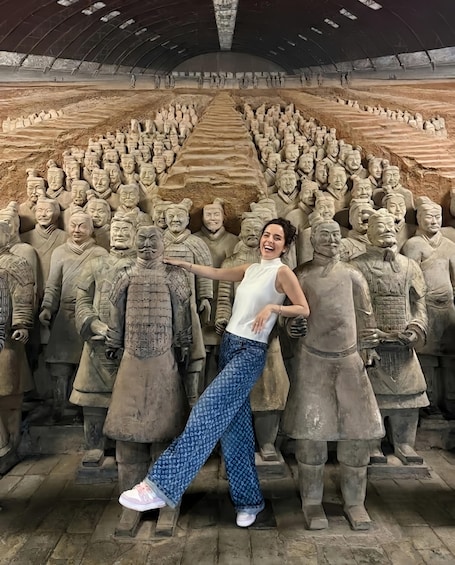 A person standing in front of a large terracotta army sculpture. 1