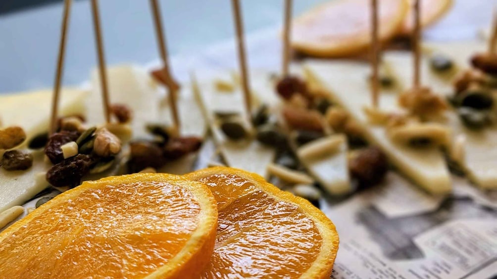 A cheese board with various cheeses, nuts, and dried orange slices. 5