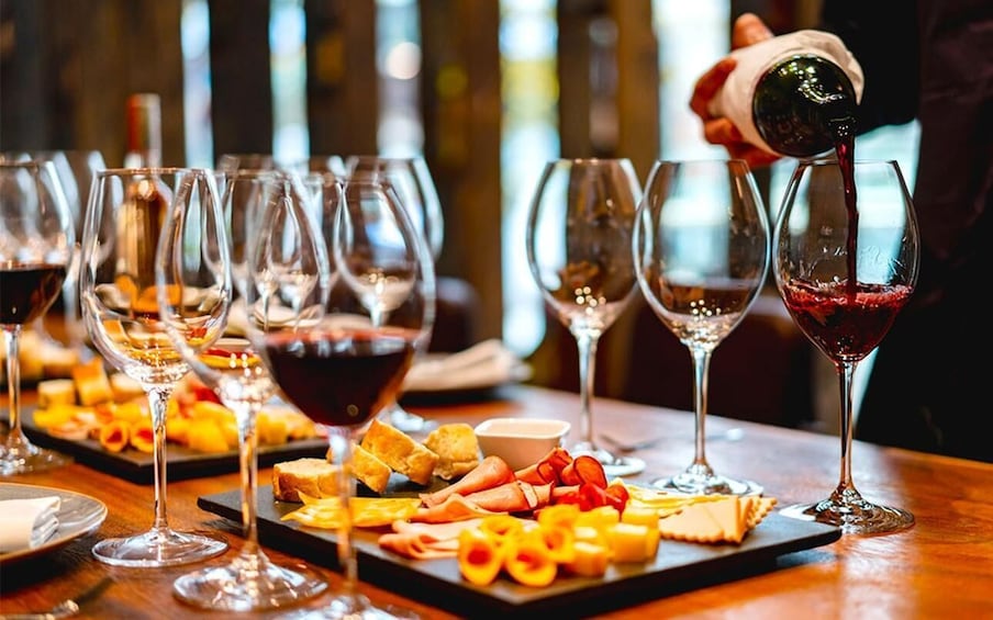 A wine tasting event with glasses of red wine and a charcuterie board. 1