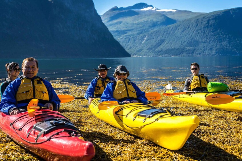 A group of people kayaking on a beach with mountains in the background. 4