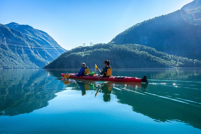 Two people kayaking on a calm lake with mountains in the background. 5