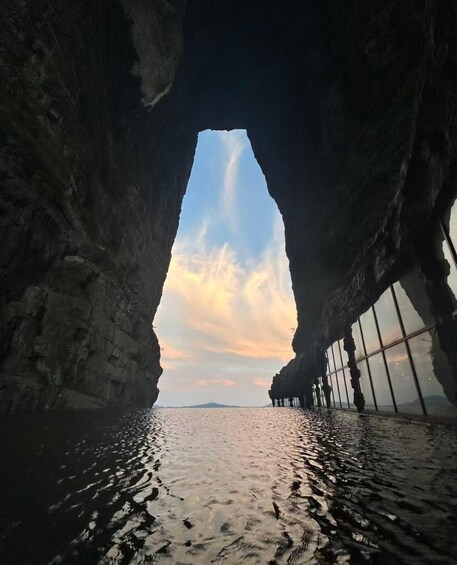 A cave opening to a body of water with a sunset sky. 2