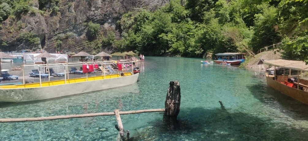 A boat docked at a pier with a forested hillside in the background. 4