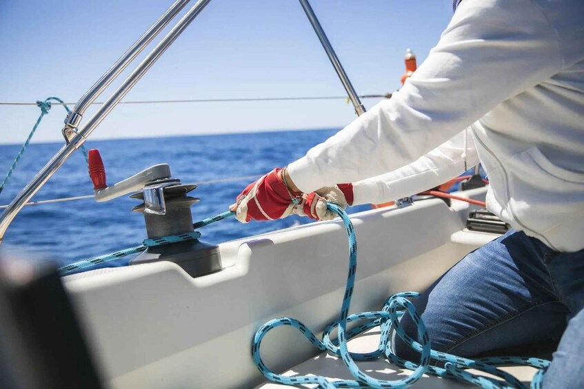 A person on a boat handling ropes and a winch. 4