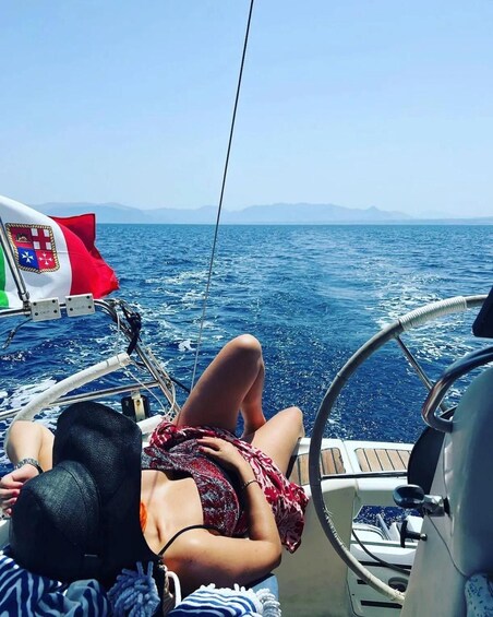 A person reclining on a boat deck, with a clear view of the sea and distant mountains. 3